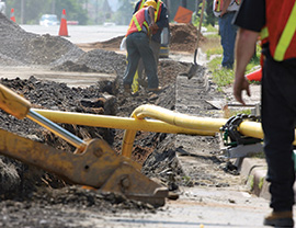 Backhoe digging and gas pipes exposed